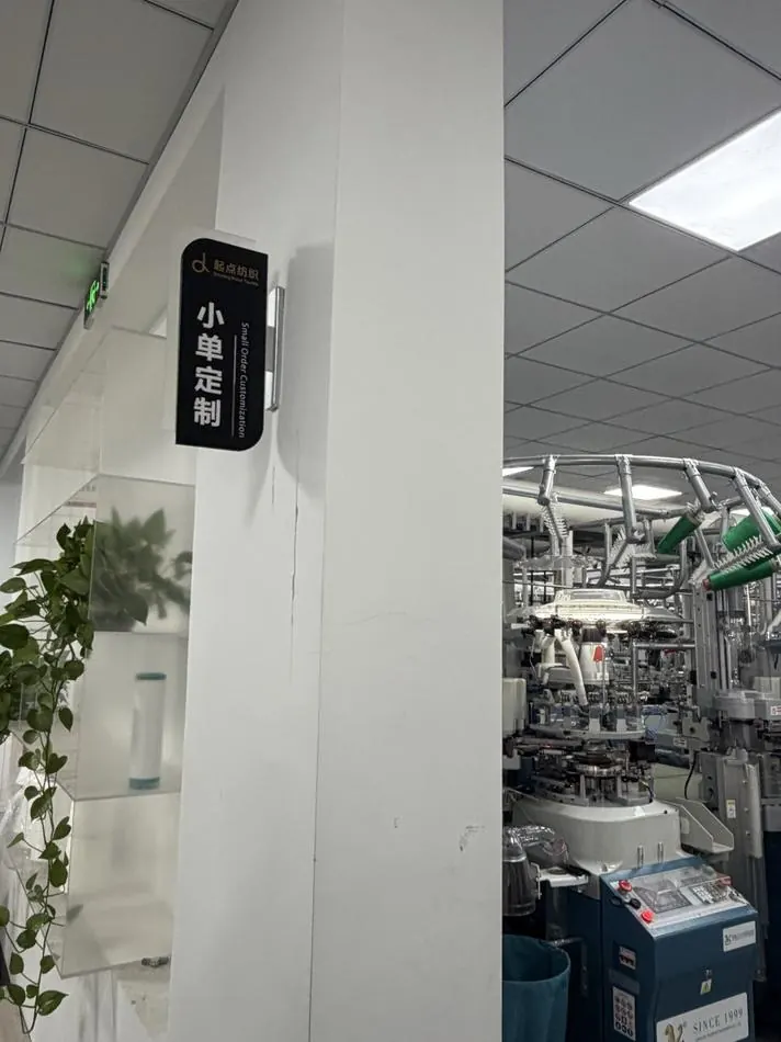 A sign over a machine row reading 小单定制 — small-batch customisation